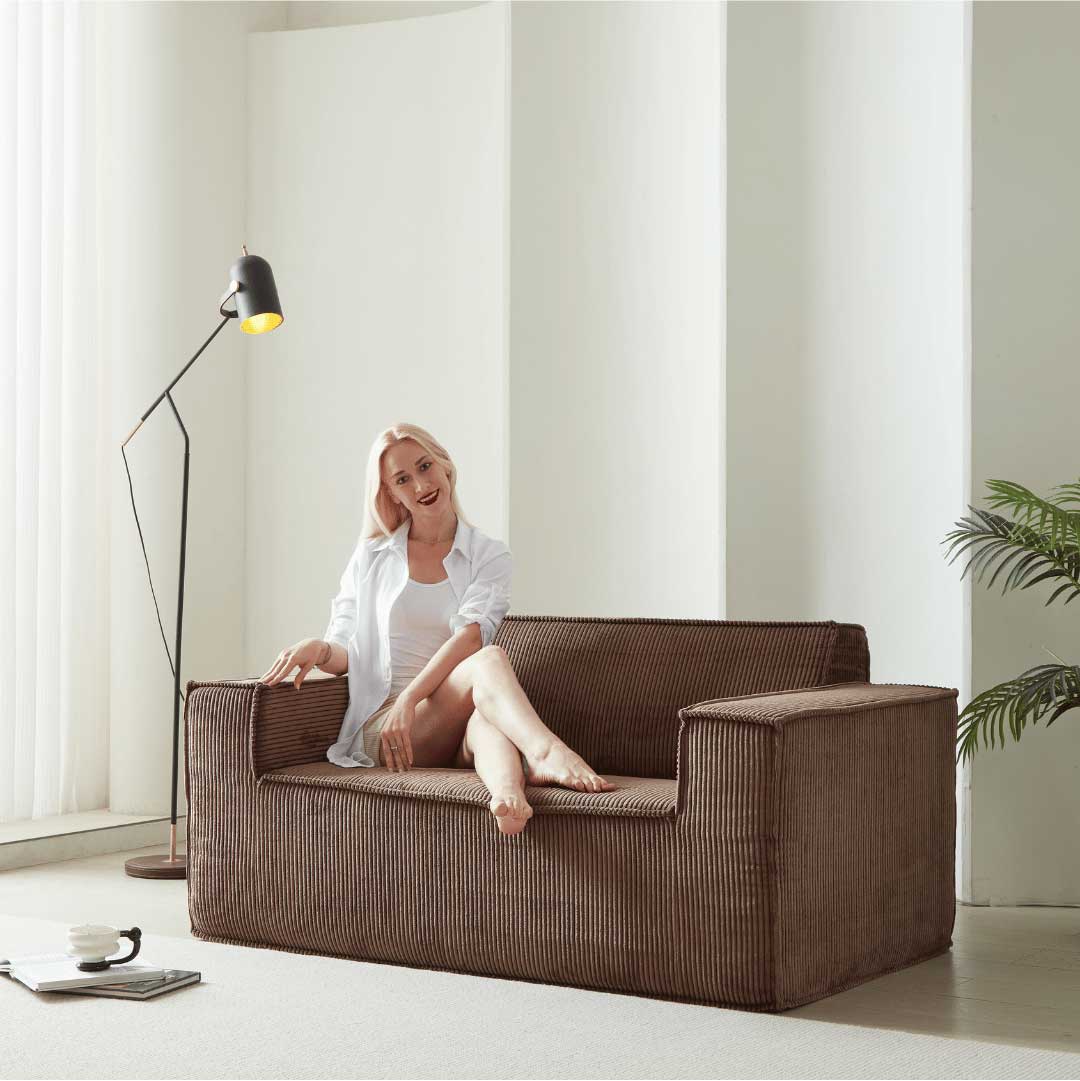 Model sitting on mocha brown Matoresu SignatureLux sofa in minimalist space
