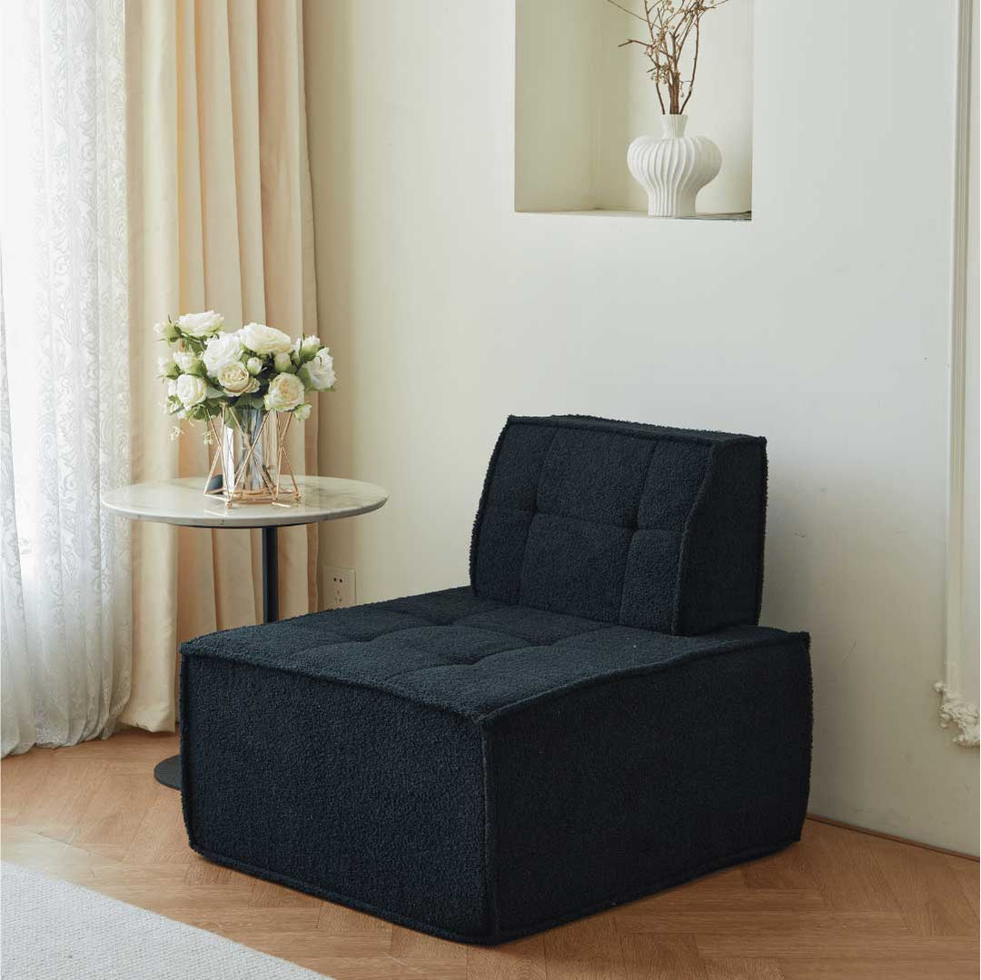 Matoresu TofuSeat™ black sherpa modular armless sofa chair next to a round marble side table with white flowers in a bright, modern interior