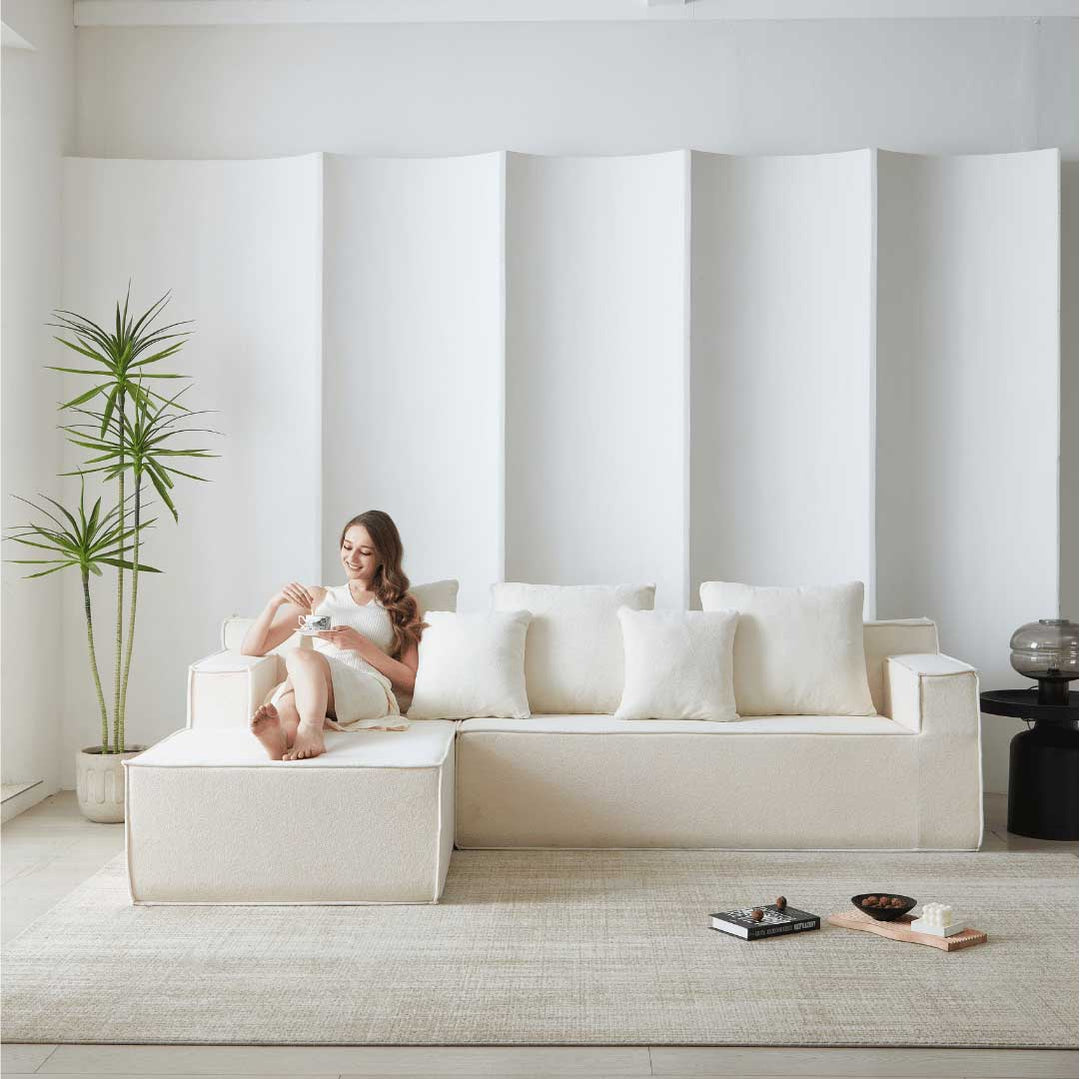 Woman relaxing on Matoresu CloudNest white memory foam sectional sofa with chaise, enjoying coffee in a minimalist living room