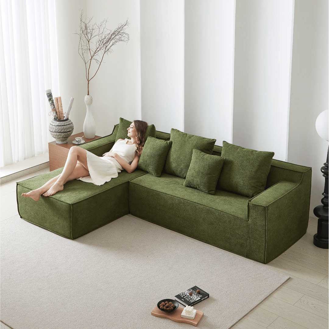 Woman lounging on Matoresu CloudNest green memory foam sectional chaise sofa in a serene minimalist living space