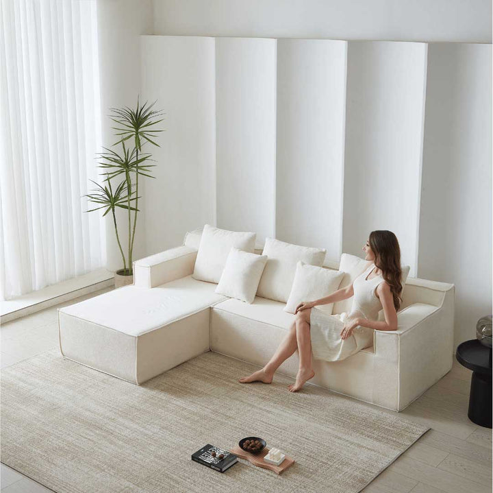 Woman sitting on Matoresu CloudNest white memory foam sectional chaise sofa in a modern minimalist living room